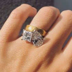 a woman's hand with two diamond rings on top of her finger and the other hand holding an engagement ring