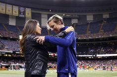 a man and woman embracing each other in front of a stadium full of people on the field