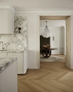 a kitchen with white cabinets and marble counter tops, along with a dining room table