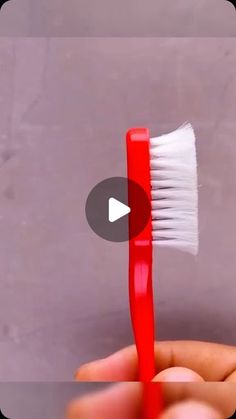 a person holding a red and white toothbrush in their left hand with the brush pointed up