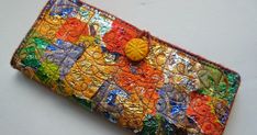 a multicolored patchwork wallet with buttons on the front and back side, sitting on a white surface