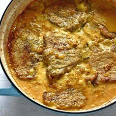 a pot filled with meat and sauce on top of a wooden table