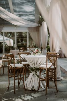 the table is set up with white linens and greenery for an outdoor wedding reception