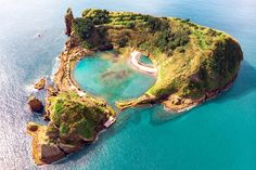 an island in the middle of the ocean surrounded by land and water with trees on it