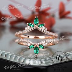 a diamond and emerald ring on top of a table