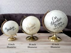 three decorative globes with names on them sitting on a table in front of a couch