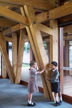 two young children standing in front of large wooden beams