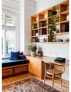 a room with a desk, chair and bookshelf filled with plants in it