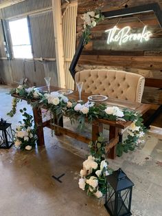 a wooden bench with flowers and greenery on the table in front of a sign that reads the bride