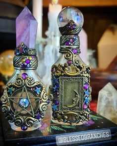 two glass bottles are sitting on a table next to each other with crystals in them