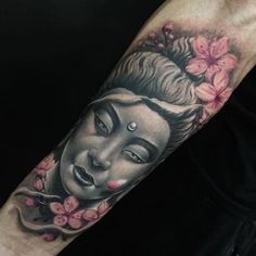 a man with a tattoo on his arm has a buddha face and flowers around him