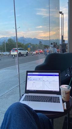 a laptop computer sitting on top of a wooden table next to a cup of coffee