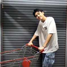 a young man holding a shopping cart in front of a garage door with shutters