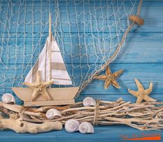 a sailboat, starfish and driftwood on a blue wooden background with rope