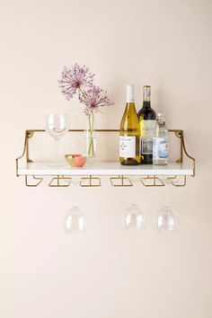 wine glasses and bottles are sitting on a shelf next to two empty glassware holders