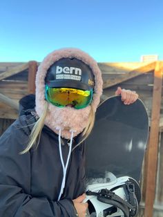 a person wearing a helmet and goggles holding a snowboard