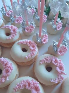 there are many donuts with pink frosting and candles in the shape of flowers