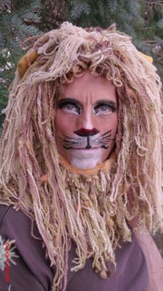 a man with long blonde hair wearing a cat mask and dreadlocks on his face