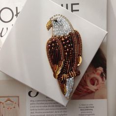 a brooch that is sitting on top of a piece of paper with beading