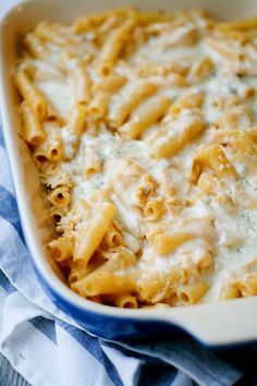 a casserole dish filled with pasta and cheese on a blue and white towel