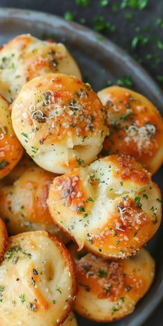 garlic bread rolls with parmesan cheese and herbs in a gray bowl on a table