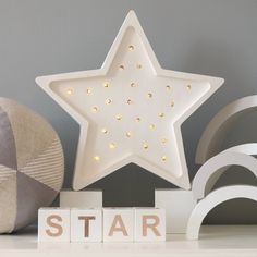 a white star shaped light sitting on top of a wooden block next to a ball