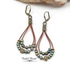 "These boho leather dangle earrings consist of 2 loops of 1mm natural brown leather cord accented with matte metallic patina iris seed beads and a bronze flower bead. The leather loops are glued into antique bronze Tibetan style cord ends. The earwires are bronze plated lever backs. The earrings measure 2 3/4\" long from the top of the earwires to the bottom of the longest loop. They are 1\" wide. All jewelry is packaged ready for gift giving as shown in the last photo. Each item comes in an org Bohemian Brown Teardrop Earrings For Gift, Bohemian Brown Teardrop Earrings Gift, Bohemian Teardrop Earrings Nickel Free For Everyday, Handmade Brown Bohemian Teardrop Earrings, Nickel-free Bohemian Brown Teardrop Earrings, Bohemian Leather Teardrop Earrings, Bohemian Teardrop Leather Earrings, Bohemian Brown Teardrop Earrings For Pierced Ears, Nickel-free Brown Teardrop Earrings For Jewelry Making