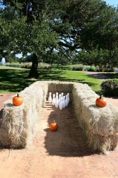 bowling pins and pumpkins are placed on hay bales