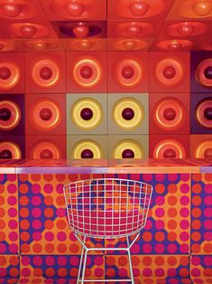 a chair sitting in front of a colorful wall with donuts on it's walls