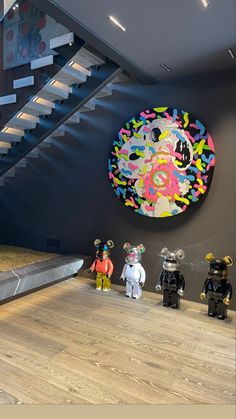 some toy figures are standing in front of a wall with a colorful painting on it