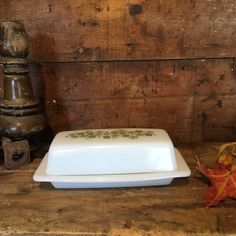 a white plate sitting on top of a wooden table next to an orange maple leaf