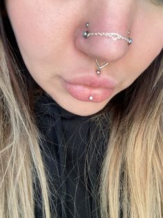 a close up of a person with piercings on her nose and nose chain attached to their nose