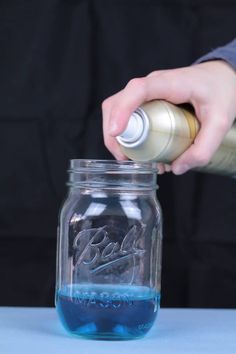 a person pouring blue liquid into a glass jar