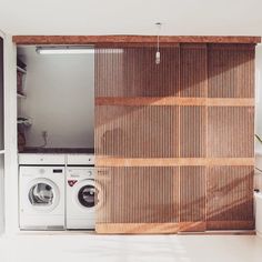 a washer and dryer in a room with wooden slats on the wall