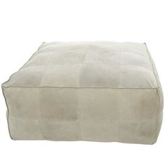 a white square footstool sitting on top of a white floor mat covered in suede