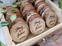 wooden slices with names on them sitting in a box surrounded by greenery and leaves