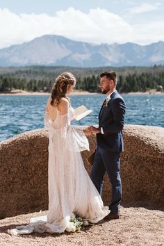 a bride and groom standing next to each other in front of the water at their wedding ceremony