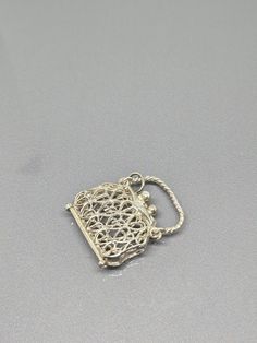 a small metal object sitting on top of a gray surface with a chain attached to it