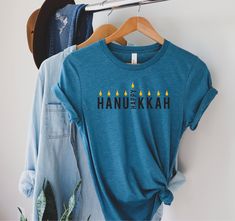 the hanukkah candles t - shirt is hanging on a rack next to jeans