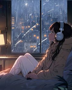 a woman with headphones sitting in front of a window looking out at the city