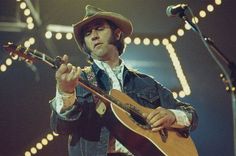 a man with a cowboy hat playing an acoustic guitar on stage at a music festival