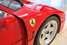 the rear end of a red sports car parked in a showroom with its door open