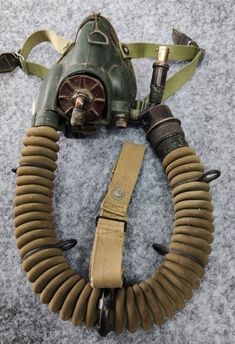 an old gas mask is laying on the floor next to a corded up hose