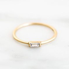 Our dainty baguette ring is the sweetest little addition to our stacking ring collection. It features a tiny little cubic zirconia baguette in the middle. Stack it with your favorite rings, or wear it alone! Find more dainty stacking rings at Simple & Dainty. Classic Baguette Rings For Everyday, Elegant Everyday Diamond Open Ring, Elegant Stackable Rings With Baguette Diamonds, Dainty Baguette Jewelry For Everyday, Elegant Everyday Diamond Ring With Baguette Diamonds, Elegant Everyday Diamond Ring With Simple Design, Chic Stackable Rings, Minimalist Gold Baguette Ring, Chic 14k Gold Rings For Everyday