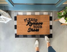 a person standing next to a door mat that says please remove your shoes