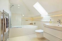 a bathroom with a toilet, sink and bathtub next to a window in the ceiling