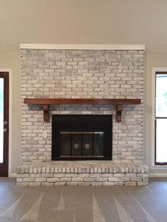 an empty living room with a fireplace and two windows