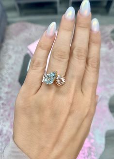 a woman's hand holding an aqua and white ring with two diamonds on it