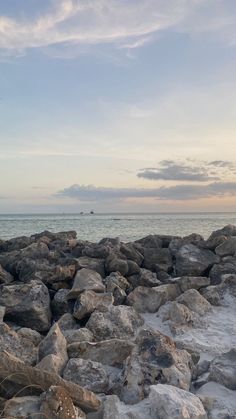 the rocks are covered with ice as the sun sets over the ocean in the distance