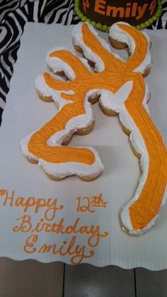 an orange and white decorated birthday cake with the letter e on it's side